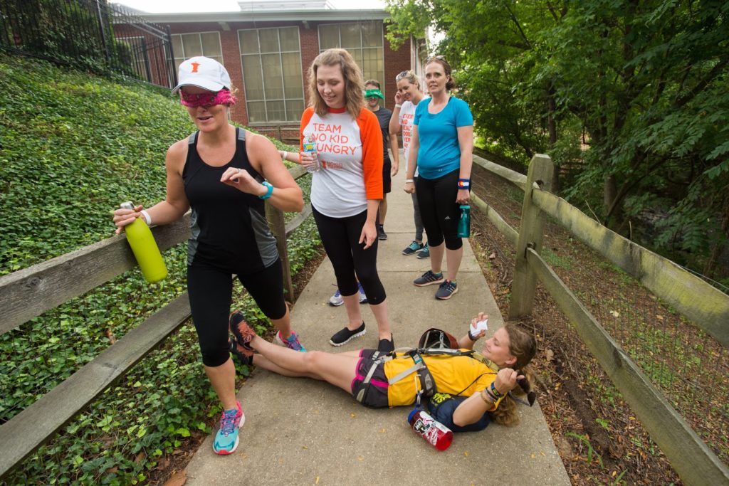 A woman instructing a blindfolded woman how to navigate obstacles.