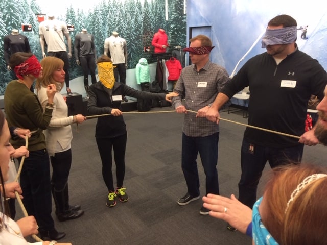 A group of blind folded people attempt to create shapes with a rope.