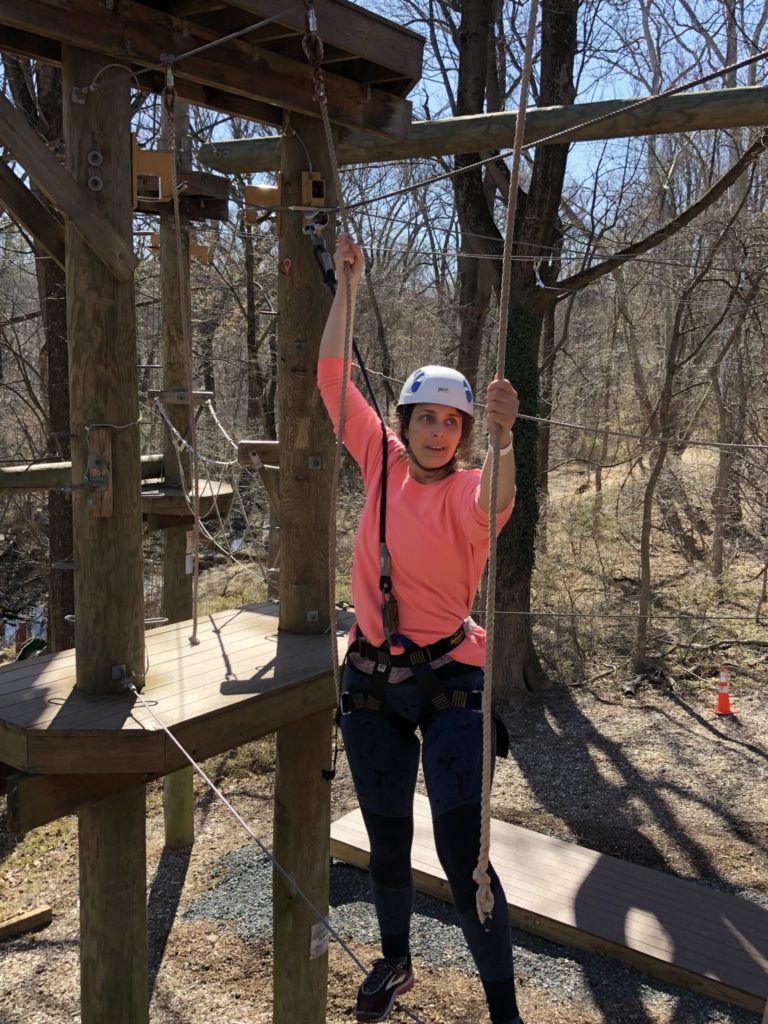 A woman swinging like Tarzan between ropes on a challenge course.